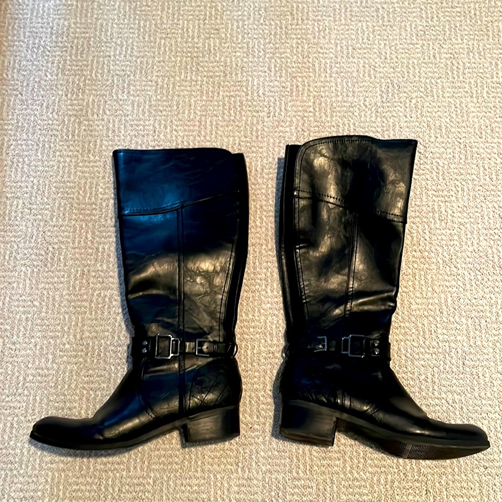 Tall black leather boots with a buckle and a small heel.